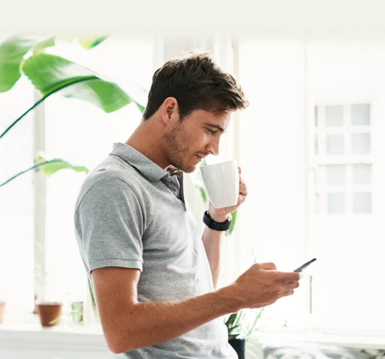 Man drinking coffee while holding mobile phone